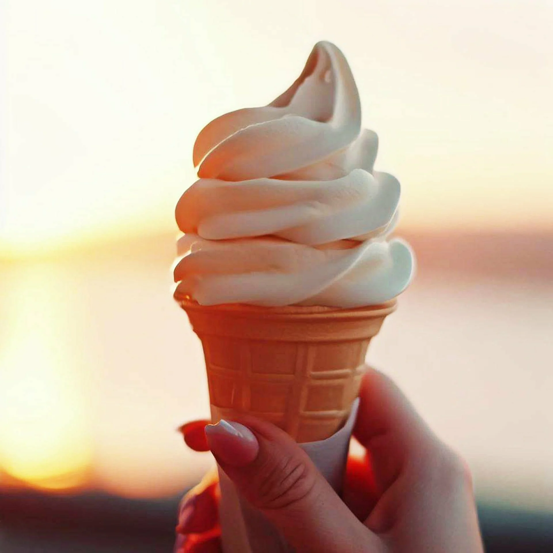Vanilla cream ice-cream cone in woman hand